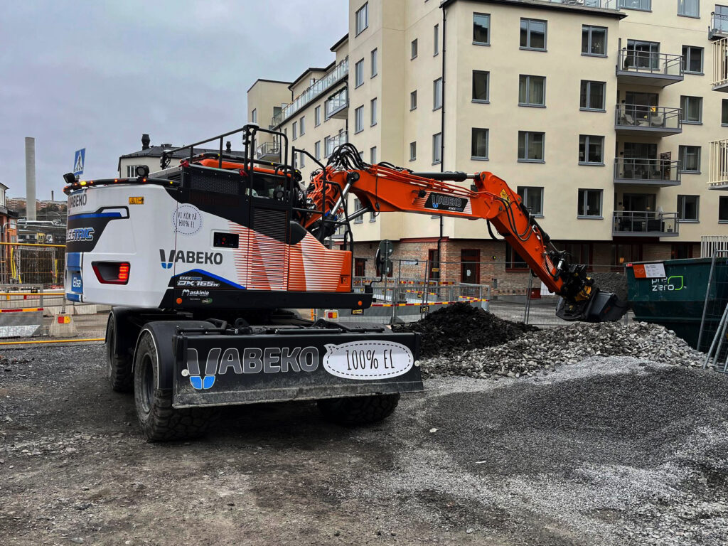 Eldriven hjulgrävare från Vabeko, Develon DX165WR Electric, arbetar på en byggarbetsplats i stadsmiljö